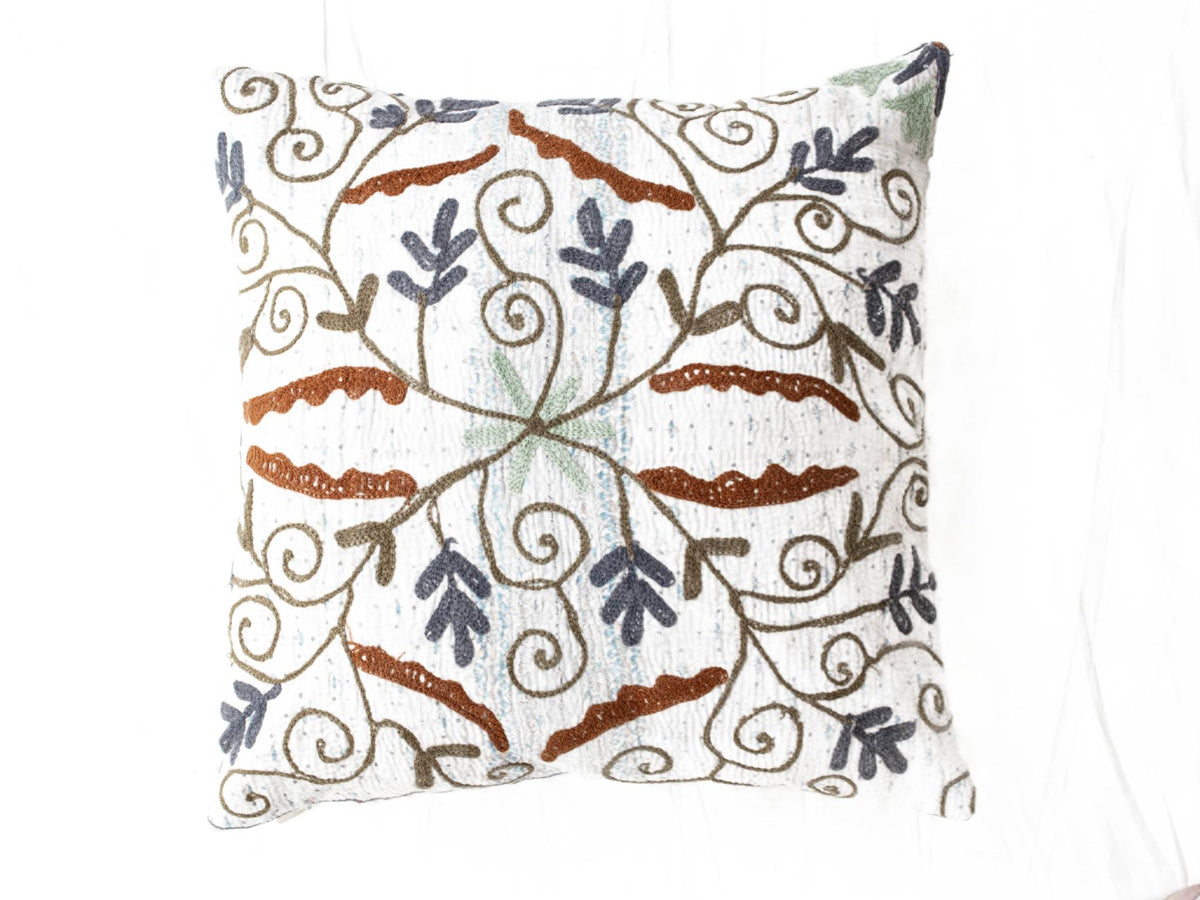 Suzani pillowcase in white with colorful embroidered loop ornaments in brown, navy, light blue and green in oriental bohemian vintage style.